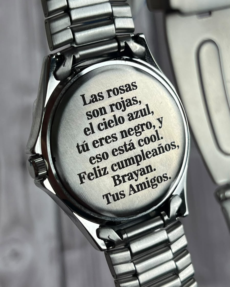 Primer plano de una dedicatoria personalizada grabada a láser en la tapa de un reloj de acero.