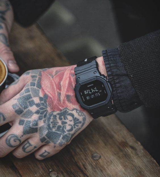 DW-5600BB-1 Casio G-Shock negro en una muñeca tatuada, con correa de resina.