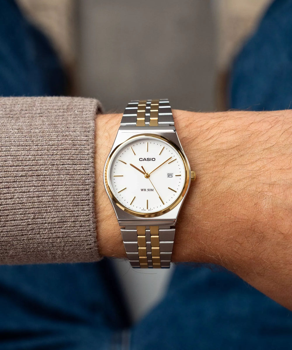 MTP-B145SG-7A Casio de esfera blanca en muñeca con brazalete bicolor plateado y dorado.