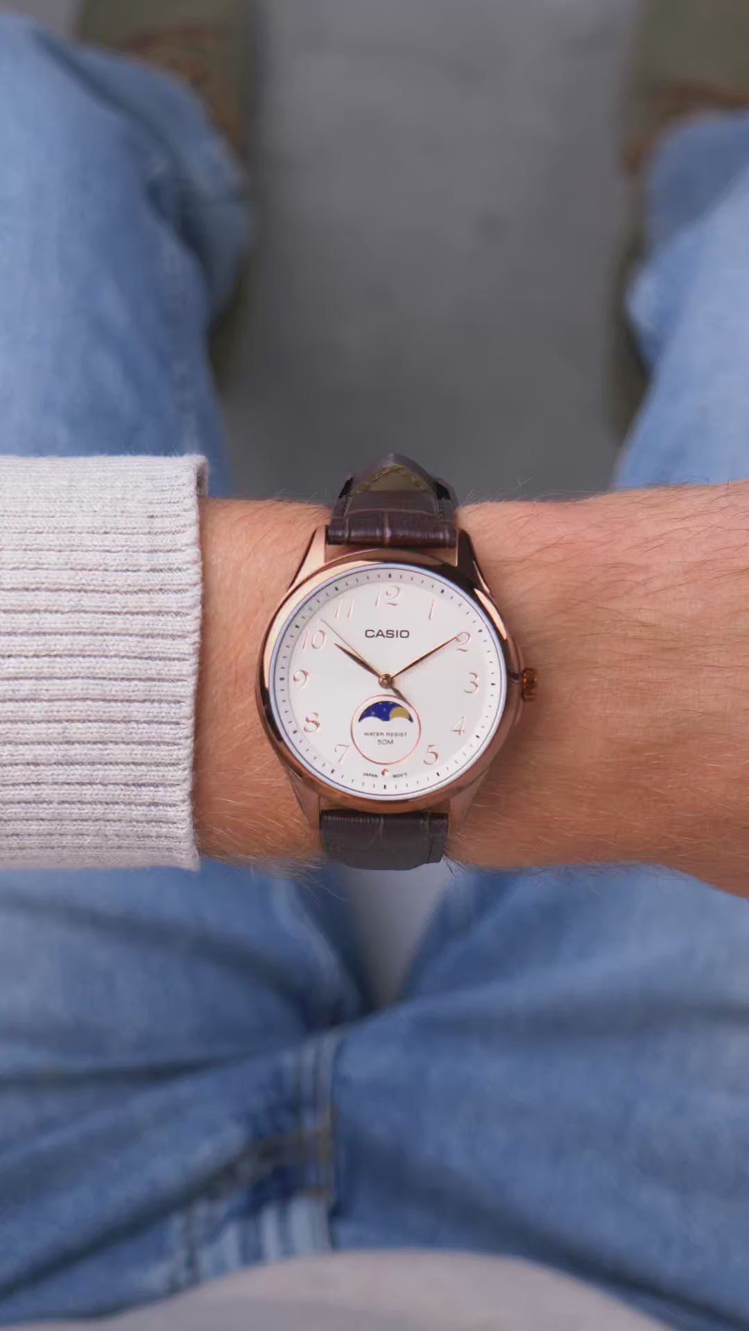 Hombre usando reloj Casio moonphase elegante con caja rose gold y correa marrón cuero sobre suéter beige | Jherr Jewelry Perú