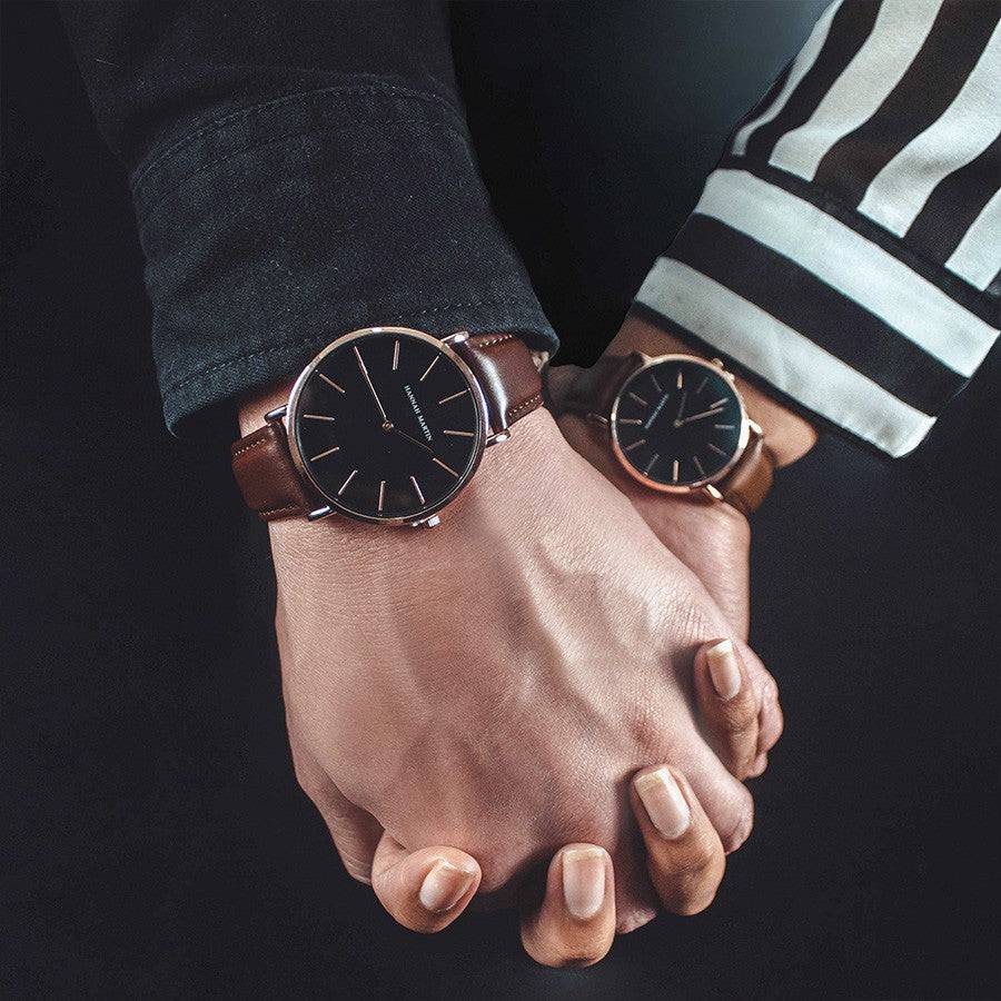 Pareja usando relojes Hannah Martin con esfera negra y correa de cuero marrón